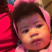 Five is registered to the contest to win money with this photo: apparel, baby, child, closeup, curly_hair, cute, expression, face, headband, headwear, human, indoor, infant, people, person, pink_clothing, portrait, sitting, skin, young_child