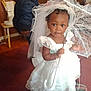 toddler, child, dress, white_dress, veil, umbrella, indoor, carpet, barefoot, curious, girl, blue_jacket, child_back, room, furniture, wooden_chair, curtain, portrait, people, floor