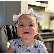 Gema Valentina joined the competition — help win amazing prizes! toddler, child, smiling, curly_hair, white_bows, high_chair, blue_shirt, cartoon_print, indoor, kitchen, happy, person, face, cute, young_child, portrait, seated, domestic, background_blur, home