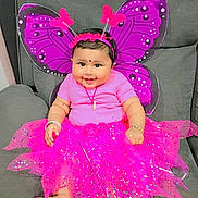 Prinjal is registered to the contest to win money with this photo: baby, child, smiling, costume, butterfly_wings, pink_tutu, headband, bracelet, sofa, indoor, cute, happy, portrait, infant, decorative, bright_colors, playful, accessories, feet, seated