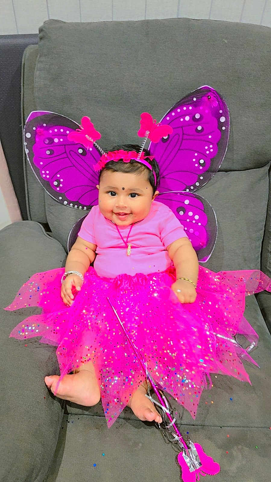 Prinjal is registered to the contest to win money with this photo: baby, child, smiling, costume, butterfly_wings, pink_tutu, headband, bracelet, sofa, indoor, cute, happy, portrait, infant, decorative, bright_colors, playful, accessories, feet, seated