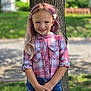 child, girl, smile, plaid_shirt, denim_shorts, tree, outdoor, grass, hair_clip, happy, portrait, cute, summer, nature, casual_clothing, standing, young, fashion, sunlight, background_blur