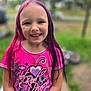 child, girl, smiling, pink_hair, purple_hair, colorful_clothing, short_sleeve_shirt, outdoor, grass, blurred_background, portrait, happy, person, youth, casual_wear, nature, daylight, face, standing, playful