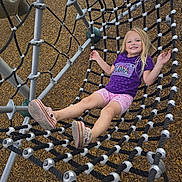 Charlotte is registered to the contest to win money with this photo: child, girl, playground, rope_net, smiling, purple_shirt, pink_shorts, sneakers, outdoor, play, happy, metal_structure, wood_chips, summer, casual_clothing, recreation, fun, young, leisure, daytime