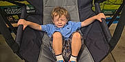 Thomas is registered to the contest to win money with this photo: child, boy, folding_chair, blue_shirt, plaid_shorts, paw_patrol_sandals, closed_eyes, gripping, indoor, store, box, packaging, floor, concrete, legs, seated, casual_clothing, short_hair, expression, toy_character