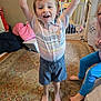 Thomas is registered to the contest to win money with this photo: child, barefoot, striped_shirt, shorts, carpet, indoor, baby_gate, toy, happy, smiling, person, home, floor, rug, furniture, window, curtain, playful, excited, family