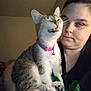 Jennifer Roberts is registered to the contest to win money with this photo: woman, cat, indoor, pet, holding, pink_collar, bell, gray_cat, white_cat, funny_face, mid_meow, expressionless, casual_clothing, human, animal, close_up, portrait, domestic, feline, companion