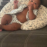 Bahri is registered to the contest to win money with this photo: baby, child, infant, couch, pillow, striped_clothing, snack, indoor, staircase, curious, brown_skin, sitting, relaxed, home, soft_lighting, portrait, furniture, hand, face, comfort