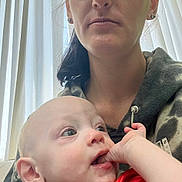 Daniel is registered to the contest to win money with this photo: baby, infant, woman, adult, face, portrait, hand, curious, indoor, curtain, clothing, hoodie, skin, expression, closeup, person, parent, child, light, natural_light