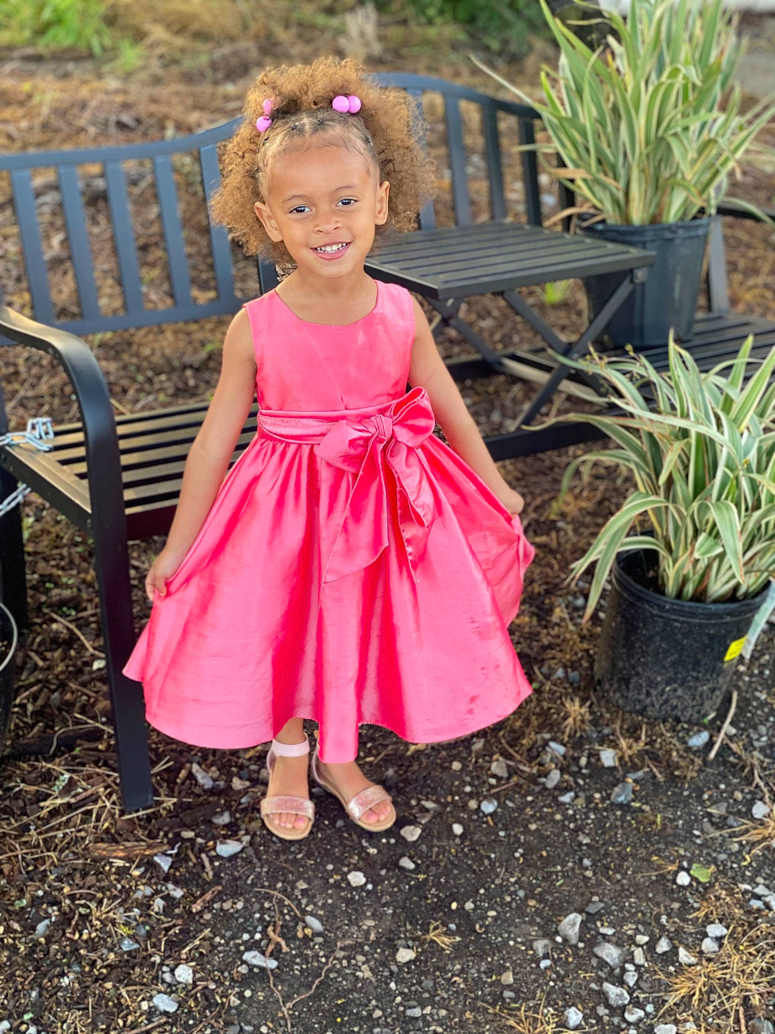 Journi is registered to the contest to win money with this photo: baby_toddler_clothing, child, day_dress, dress, face, flowerpot, garden, grass, grass_family, happy, houseplant, joy, landscape, magenta, people_in_nature, person, pink, plant, shrub, smile