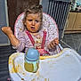 Everleigh is registered to the contest to win money with this photo: baby_gate, child, clothing, cup, emotion, expression, face, floor, food, high_chair, indoor, kitchen, messy, person, pink, seatbelt, sippy_cup, table, toddler, unicorn_pattern