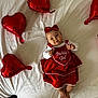 baby, child, red_dress, headband, heart_balloon, bed, white_bed_sheet, infant, cute, portrait, holiday_theme, celebration, indoors, lying_down, adorable, festive, clothing, person, smiling, baby_girl