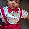 baby, bed, bedding, bow_tie, child, cute, expression, face, formalwear, indoor, infant, looking_at_camera, lying_down, pants, patterned_shirt, photography, portrait, red_clothing, shirt, suspenders