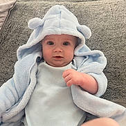 Parker joined the competition — help win amazing prizes! baby, infant, blue_blanket, hood, bear_ears, soft_texture, plush, pillow, gray_background, cute, child, person, clothing, indoor, portrait, young, lying_down, skin, face, hand