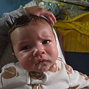 William joined the competition — help win amazing prizes! baby, infant, face, pajamas, clothing, hand, blanket, couch, indoor, portrait, expression, curious, furrowed_brow, child, person, soft_lighting, closeup, home, resting, cozy