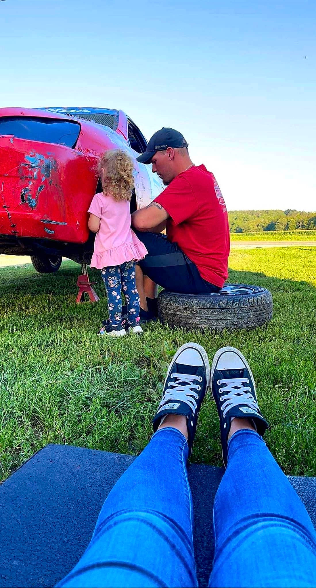 Lola is registered to the contest to win money with this photo: automotive_design, automotive_exterior, automotive_lighting, blue, bumper, car, clothing, grass, happy, headwear, leisure, morning, motor_vehicle, people_in_nature, person, plant, shoe, shorts, sky, summer