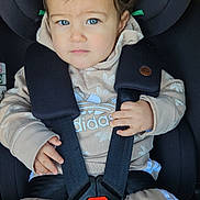 Noé a rejoint le concours — aidez-le/la à gagner de superbes lots ! toddler, child, car_seat, seatbelt, blue_eyes, beige_clothing, hoodie, tracksuit, baby, straps, safety, portrait, indoor, cute, curly_hair, person, young_child, serious_expression, hands, casual_wear