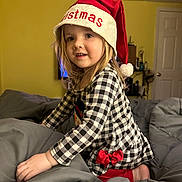 Aurora joined the competition — help win amazing prizes! child, christmas_hat, checkered_dress, red_bow, blanket, indoor, smiling, blonde_hair, bedroom, yellow_wall, door, furniture, home, holiday, festive, happy, person, portrait, cute, toddler
