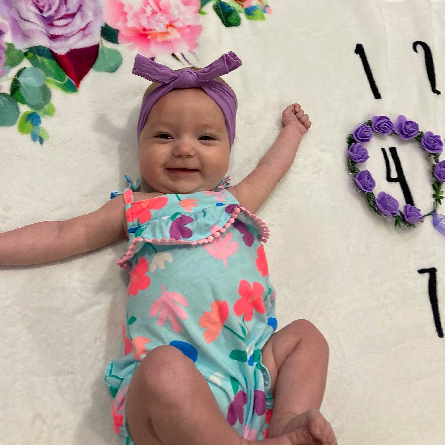 Sydney is registered to the contest to win money with this photo: baby, baby_toddler_clothing, dress, facial_expression, finger, flower, happy, headgear, headwear, joy, person, petal, photograph, pink, plant, product, purple, skin, sleeve, smile