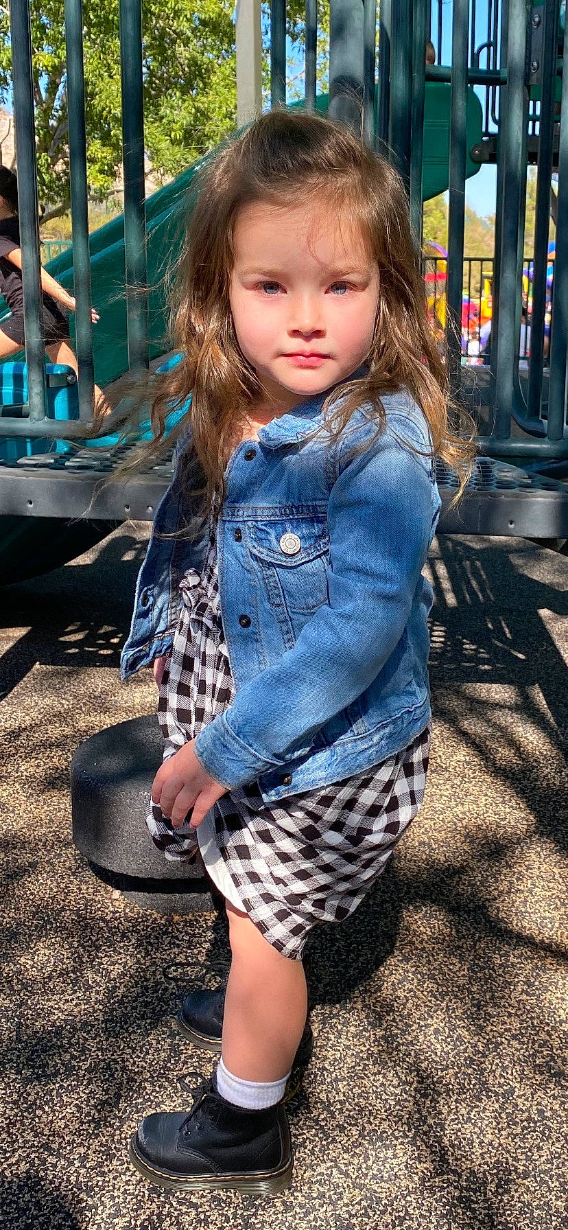 Charlotte is registered to the contest to win money with this photo: cool, denim, eye, face, facial_expression, fun, grass, hairstyle, happy, human, outerwear, people, person, plaid, sleeve, standing, street_fashion, tartan, toddler, waist