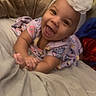 baby, smiling, headband, flower, bed, blanket, happy, infant, child, clothing, indoors, portrait, cute, toddler, hands, lying_down, person, soft_lighting, cozy, warm