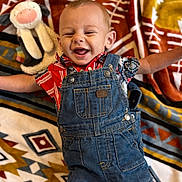 Hudson is registered to the contest to win money with this photo: baby, denim_overalls, smiling, stuffed_animal, colorful_clothing, blanket, patterned_blanket, happy, infant, cute, lying_down, child, toy, soft_toy, fabric, portrait, indoors, small_child, playful, joyful