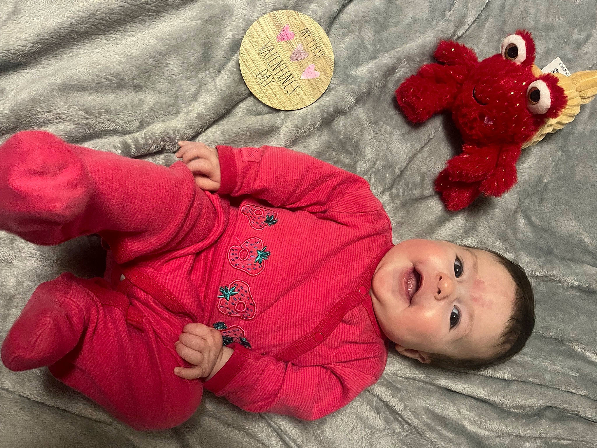 Josie is registered to the contest to win money with this photo: baby, baby_products, baby_sleeping, baby_toddler_clothing, carmine, child, comfort, flooring, fur, happy, linens, person, red, sitting, skin, sleeve, smile, stuffed_toy, toddler, toy