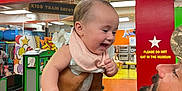 Dana Marylynn joined the competition — help win amazing prizes! baby, man, indoor, play_area, child, smiling, holding, colorful, bib, beard, toy_train, furniture, sign, person, happy, laughter, clothing, arm, background, interaction