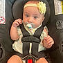 baby, infant, car_seat, pacifier, headband, yellow_flower, straps, black, clothing, cute, child, sitting, looking, face, hands, legs, safety, seatbelt, closeup, indoors
