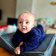 Marceau a rejoint le concours — aidez-le/la à gagner de superbes lots ! baby, infant, child, blue_eyes, navy_blue_clothing, cushion, indoor, soft_fabric, curious_expression, tummy_time, pale_skin, short_hair, blond_hair, focus, portrait, person, floor, home, cozy, cute
