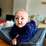 baby, infant, child, blue_eyes, navy_blue_clothing, cushion, indoor, soft_fabric, curious_expression, tummy_time, pale_skin, short_hair, blond_hair, focus, portrait, person, floor, home, cozy, cute