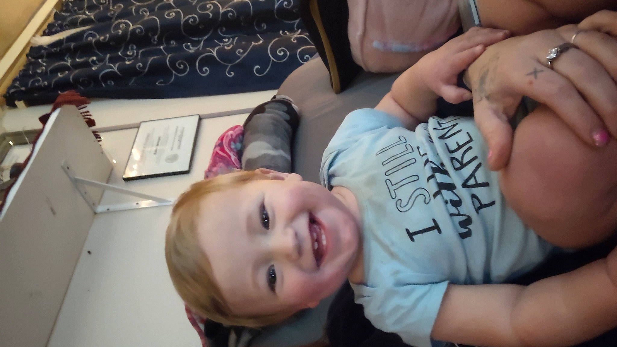 Ryker is registered to the contest to win money with this photo: chest, child, comfort, elbow, eyelash, eyewear, finger, fun, gesture, happy, human_leg, joy, mouth, nail, person, sitting, smile, t_shirt, thigh, thumb