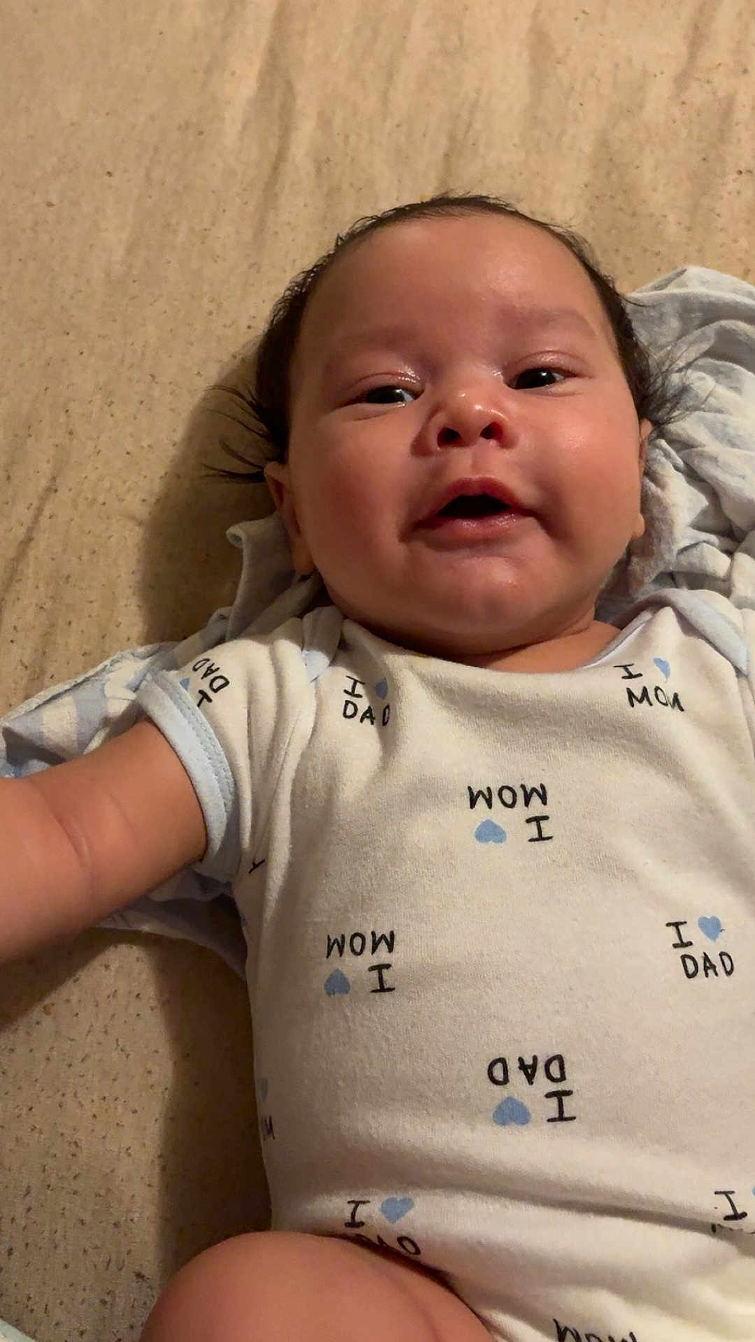 Swayde is registered to the contest to win money with this photo: baby, infant, onesie, clothing, bed, blanket, smiling, face, person, cute, child, lying_down, indoors, happy, newborn, skin, head, arm, young_child, portrait
