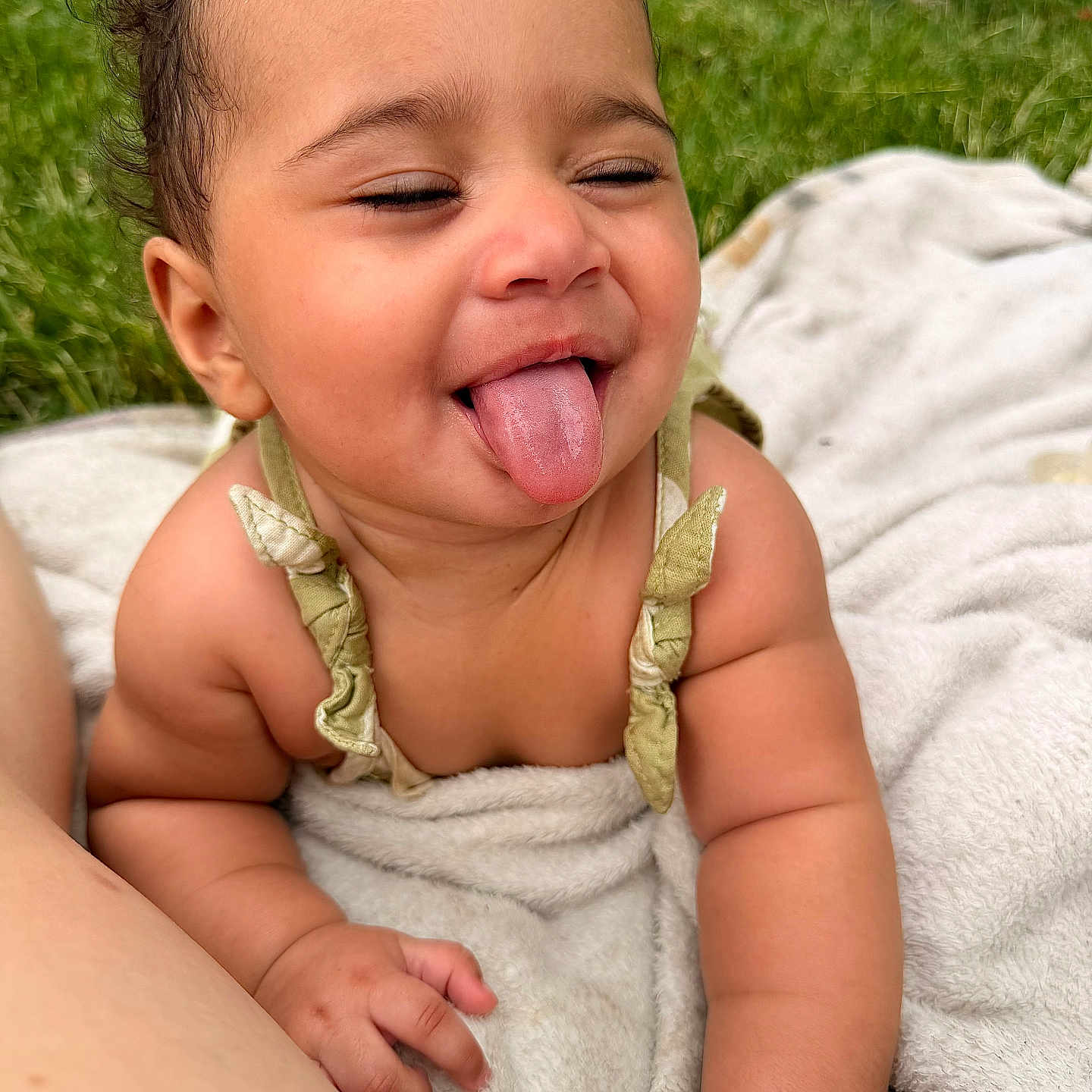 Geminiya joined the competition — help win amazing prizes! baby, tongue_out, curly_hair, blanket, outdoor, grass, playful, happy, infant, person, cute, skin, smiling, child, nature, summer, fun, closeup, face, expression