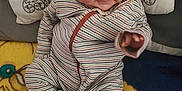 Celeste is registered to the contest to win money with this photo: baby, infant, striped_clothing, pillow, blanket, smiling, hand, face, cute, lying_down, indoors, child, young, cozy, colorful, patterned, fabric, person, portrait, cute_expression