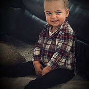 Wyatt is registered to the contest to win money with this photo: baby, black_pants, casual, child, clothing, couch, cozy, cute, face, happy, home, indoor, person, plaid_shirt, portrait, sitting, smiling, soft_surface, toddler, young_child