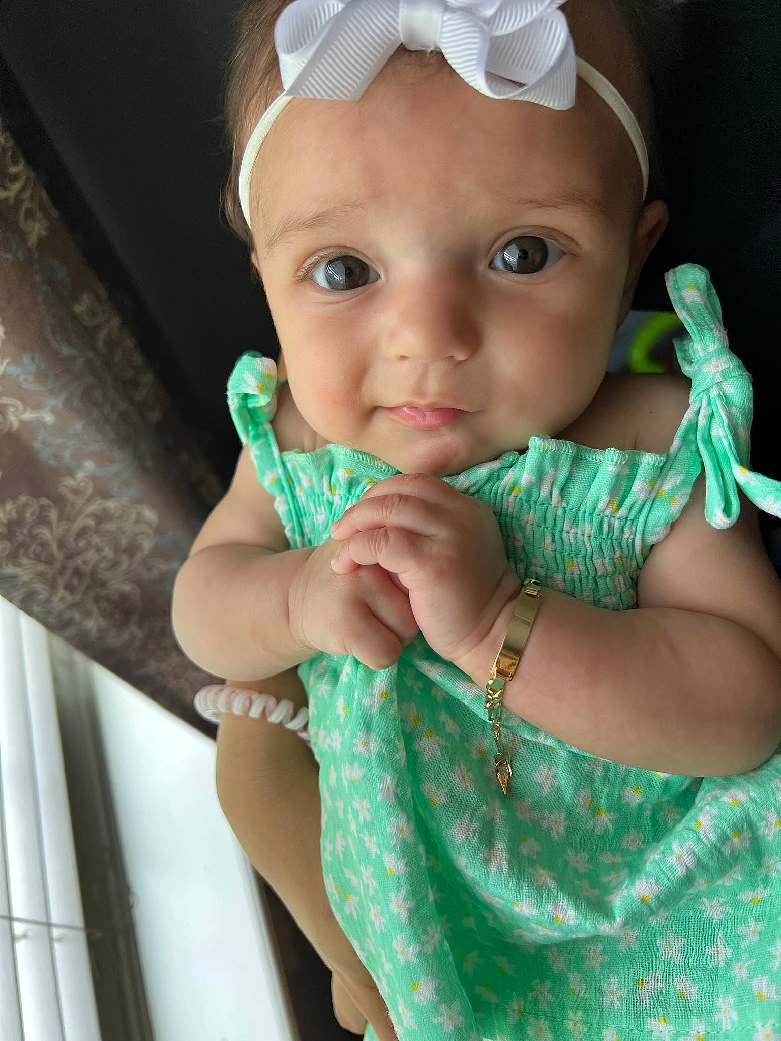 Hannah is registered to the contest to win money with this photo: arm, baby, baby_toddler_clothing, cap, child, electric_blue, eyelash, fashion_accessory, gesture, green, hand, happy, headpiece, iris, jewellery, nail, neck, person, sleeve, thumb
