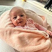 Victoire a rejoint le concours — aidez-le/la à gagner de superbes lots ! baby, infant, blanket, pink, striped_clothing, face, indoor, floor, window, curtains, natural_light, person, child, soft_texture, cozy, cute, newborn, wrapped, smile, hand