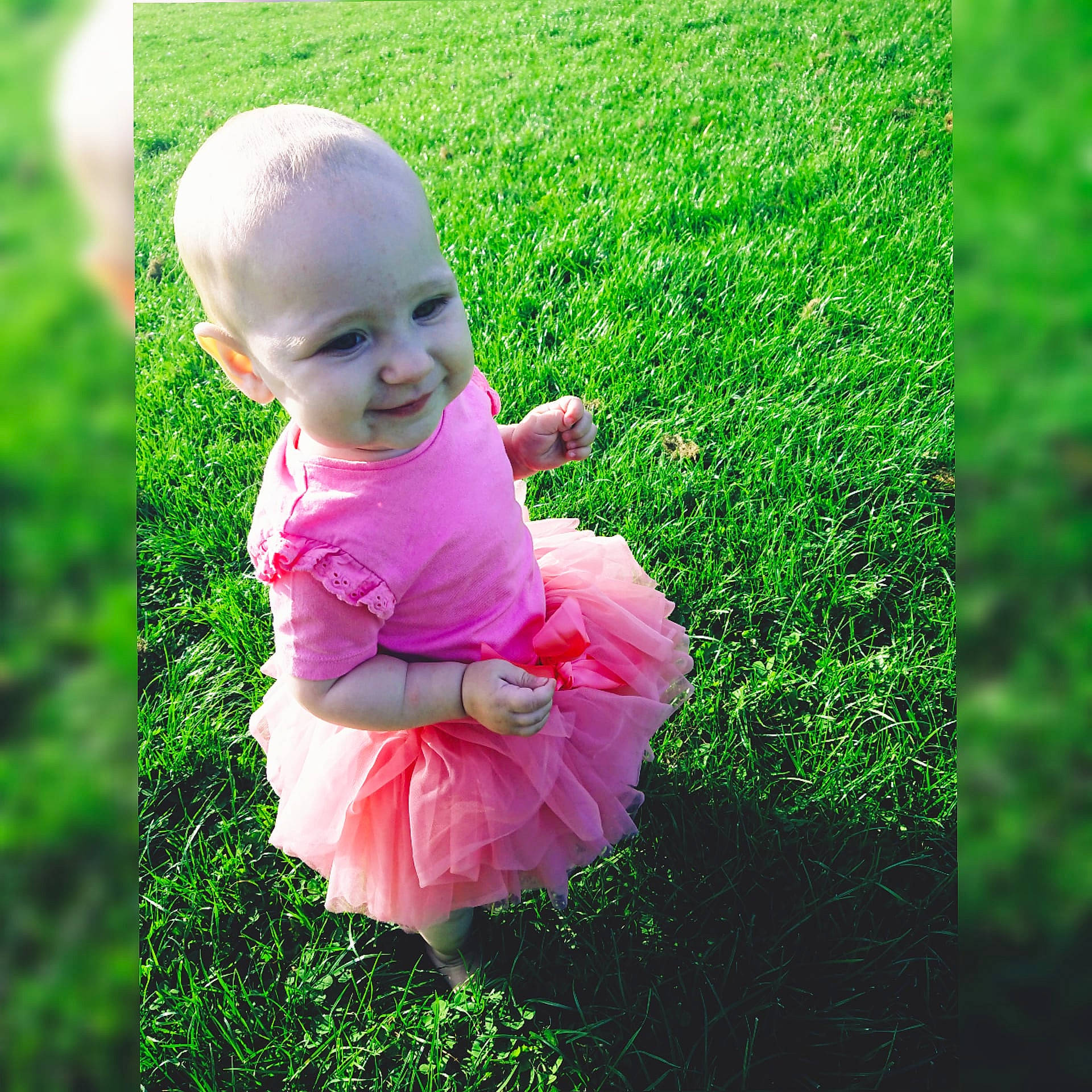 Rebecca is registered to the contest to win money with this photo: baby, baby_toddler_clothing, botany, finger, gesture, grass, green, groundcover, hand, happy, joy, leaf, natural_environment, people_in_nature, person, petal, pink, plant, smile, summer