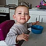 Alya a rejoint le concours — aidez-le/la à gagner de superbes lots ! child, toddler, highchair, bowl, kitchen, table, face, smile, tongue_out, ear, eyes, stove, sink, faucet, cabinet, cupboard, plastic_bowl, casual_clothing, mealtime, portrait