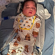 Jeremy is registered to the contest to win money with this photo: baby, sleeping, pajamas, bear_pattern, bib, medical_tube, blanket, star_pattern, infant, cute, child, lying_down, indoors, soft_lighting, face, head, yellow_sock, white_clothing, bed, rest