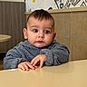 Adam joined the competition — help win amazing prizes! baby, child, infant, portrait, sitting, table, gray_sweater, wide_eyes, serious_expression, indoors, restaurant, cafe, wall_art, tiles, wood_paneling, hands, face, short_hair, looking_at_camera, close_up