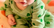 Lyla joined the competition — help win amazing prizes! baby, blanket, child, close_up, colorful, curious, cute, eyes, face, feet, green_outfit, hands, hat, indoor, infant, nursery, portrait, shamrock, sitting, soft_lighting