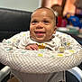baby, smile, infant, baby_seat, clothing, pattern, happy, child, indoor, person, cute, seated, face, head, eyes, mouth, tongue, skin, cheerful, furniture