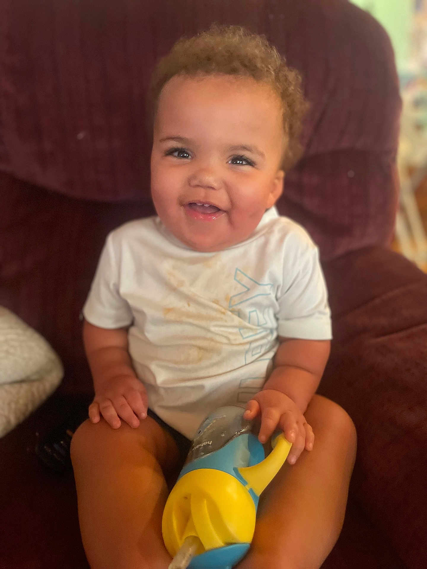 Princtyn joined the competition — help win amazing prizes! toddler, child, smiling, sippy_cup, white_shirt, messy_shirt, curly_hair, happy, indoor, chair, plush, seated, person, face, skin, hand, legs, furniture, casual, relaxed