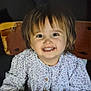 toddler, child, smiling, happy, face, portrait, table, wooden_chair, clothing, floral_pattern, long_sleeves, hands, indoor, cute, young_child, person, casual, bright_eyes, baby, seated