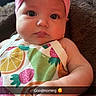 baby, infant, child, headband, pink_bow, fruit_pattern, colorful_clothing, blanket, brown_blanket, cute, portrait, closeup, indoors, resting, hand, face, eyes, expression, soft_lighting, text_overlay
