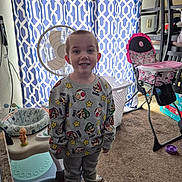 Dakota joined the competition — help win amazing prizes! child, smiling, indoor, carpet, curtain, fan, sweatshirt, pants, barefoot, toy, highchair, laundry_basket, baby_item, furniture, floor, person, room, pattern, clothing, happy