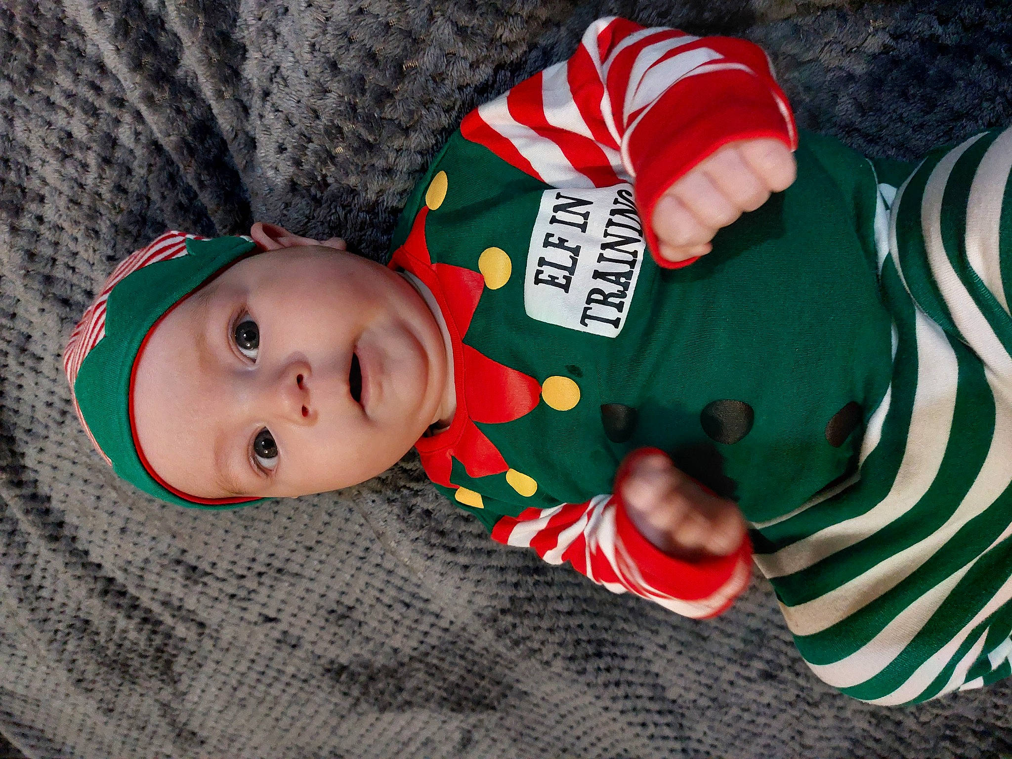 Beauden is registered to the contest to win money with this photo: baby, baby_toddler_clothing, carmine, child, christmas, christmas_eve, comfort, event, face, fictional_character, grass, hat, head, headwear, holiday, human_body, lap, pattern, person, sleeve