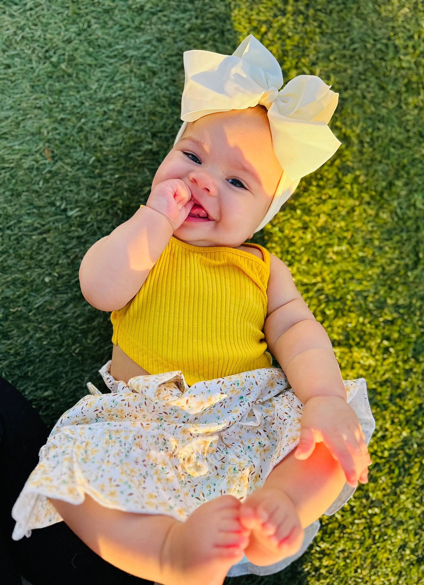 Kalina is registered to the contest to win money with this photo: baby, baby_toddler_clothing, child, costume_hat, day_dress, dress, finger, fun, grass, happy, headband, headwear, human_leg, pattern, people_in_nature, person, pink, sitting, sleeve, smile